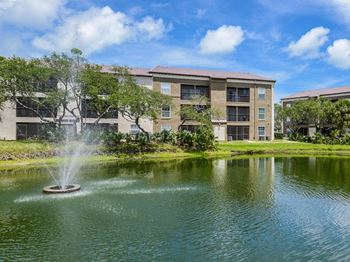 A fountain in the middle of a pond with a building in the background